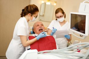 How Much Do Permanent Dentures Cost - 70 years old in dentist office have teeth check up with dental tools
